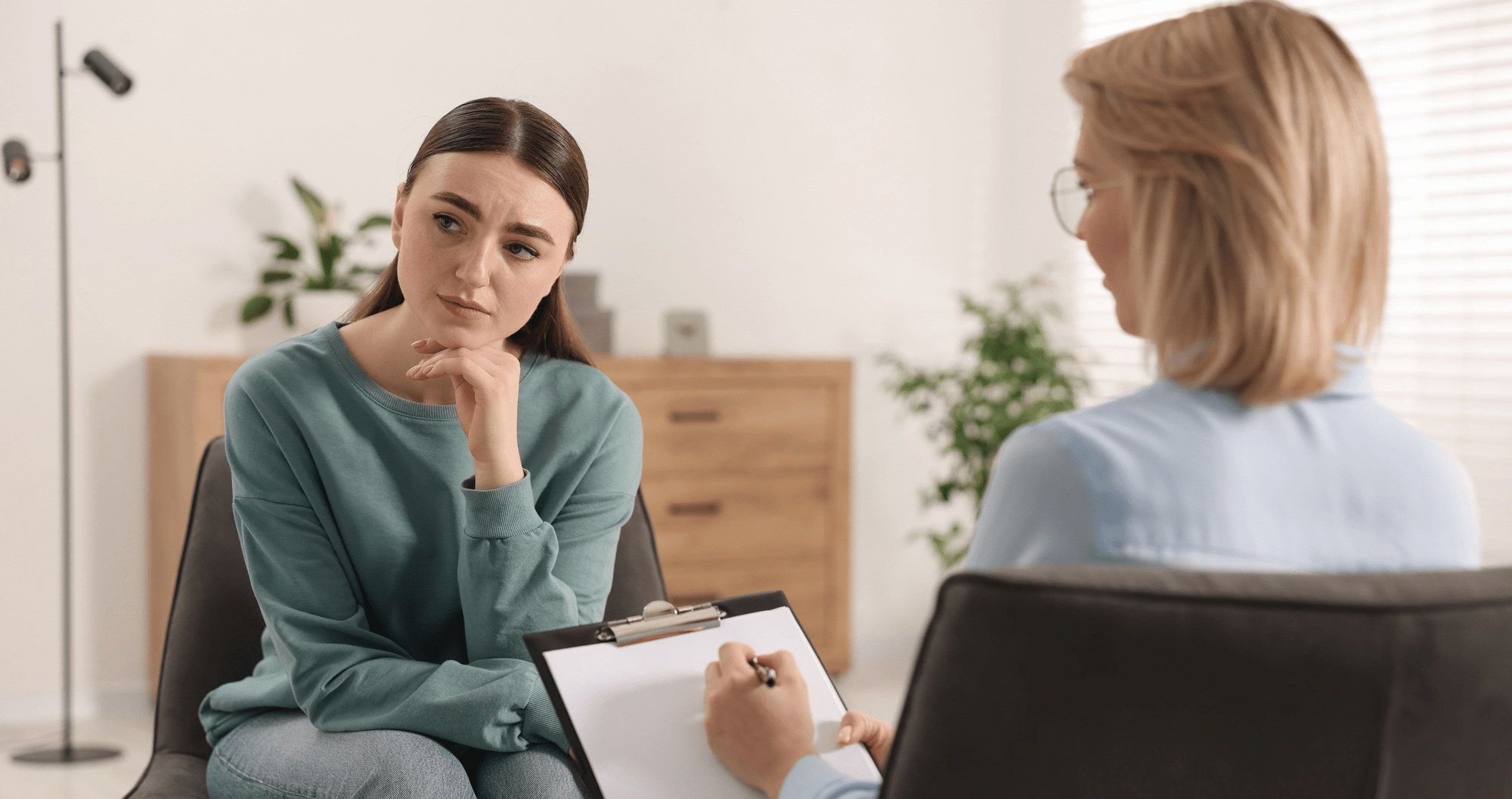 A therapist listens intently as a client reflects thoughtfully during a counseling session, highlighting the importance of mental health support.